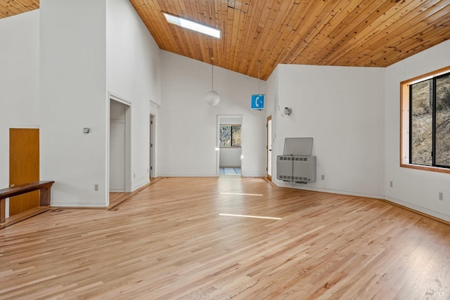 unfurnished living room with baseboards, wooden ceiling, light wood-style flooring, heating unit, and high vaulted ceiling