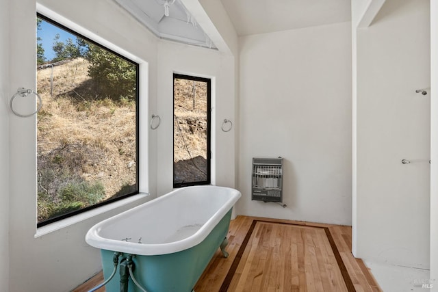 full bathroom with a freestanding tub, heating unit, and wood finished floors