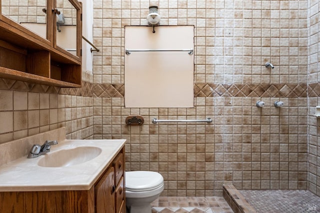 bathroom with tile walls, a tile shower, vanity, and toilet