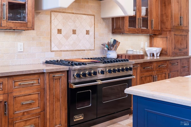 kitchen featuring tasteful backsplash, double oven range, glass insert cabinets, and brown cabinetry