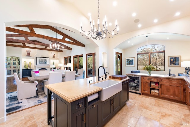 kitchen with beverage cooler, vaulted ceiling with beams, a sink, and an inviting chandelier