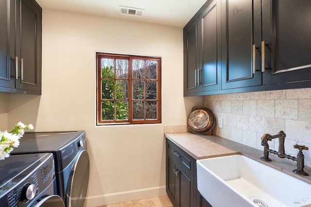 clothes washing area with a sink, visible vents, baseboards, washer and dryer, and cabinet space