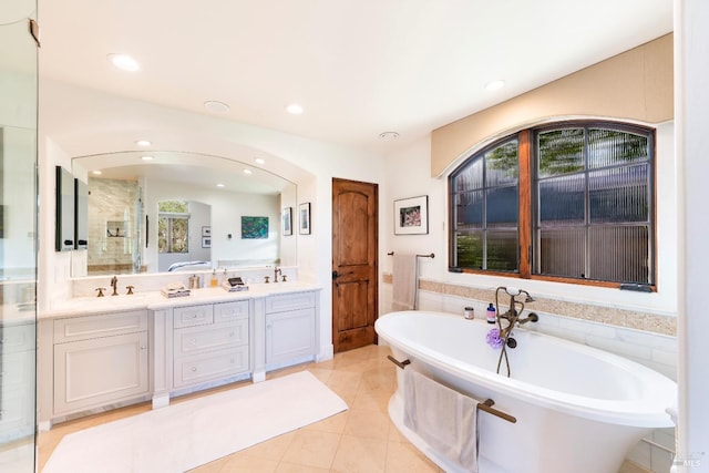 bathroom with double vanity, a stall shower, a soaking tub, tile patterned floors, and recessed lighting