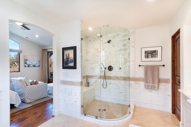 full bath featuring a wainscoted wall, tile walls, connected bathroom, a shower stall, and tile patterned flooring