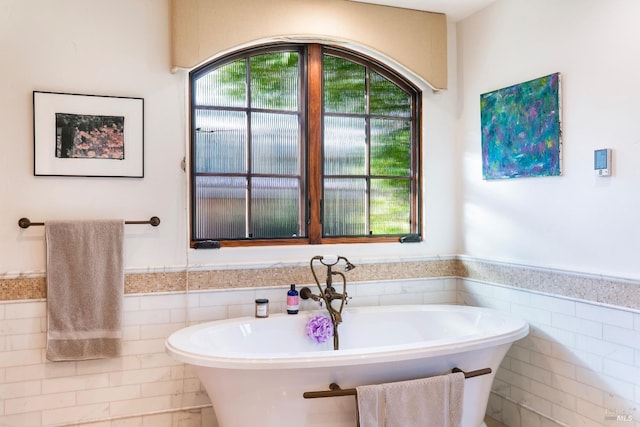 bathroom featuring a freestanding tub, a wainscoted wall, and tile walls