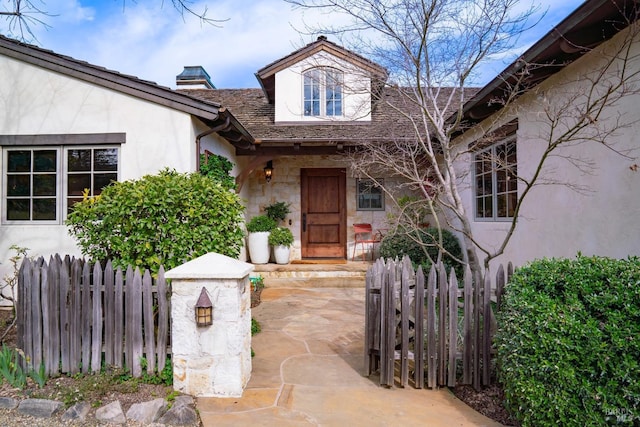 entrance to property featuring fence and stucco siding