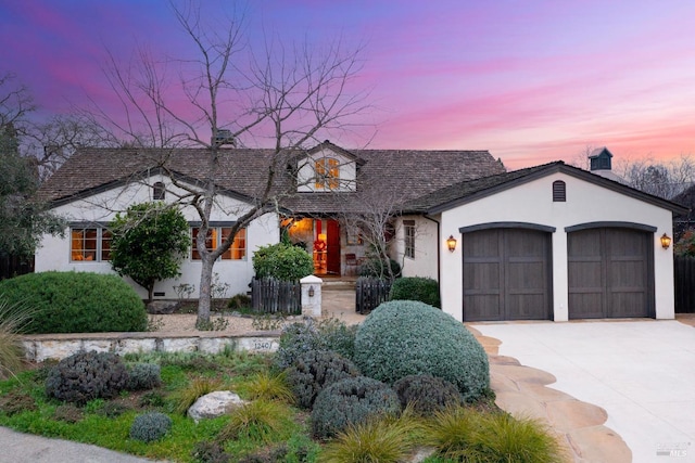 view of front of house featuring a garage, driveway, a chimney, and stucco siding