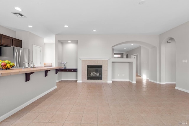 unfurnished living room with light tile patterned floors, baseboards, visible vents, a sink, and recessed lighting