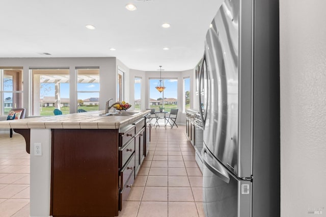 kitchen with tile countertops, light tile patterned flooring, a sink, and freestanding refrigerator