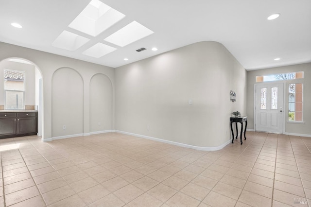 spare room featuring arched walkways, light tile patterned floors, recessed lighting, visible vents, and baseboards