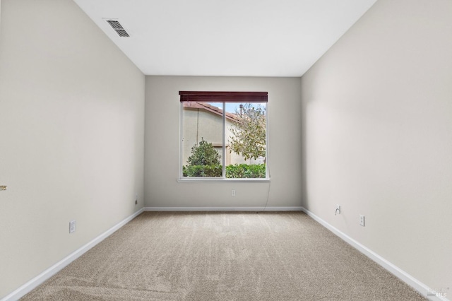 empty room with carpet floors, visible vents, and baseboards