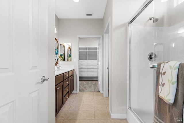 full bath with tile patterned flooring, vanity, visible vents, a spacious closet, and a shower stall
