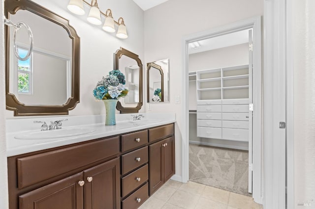 bathroom with tile patterned floors, a sink, a spacious closet, and double vanity