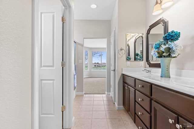 bathroom featuring double vanity, tile patterned flooring, baseboards, and a sink