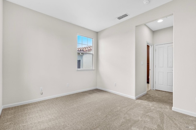 empty room with carpet flooring, visible vents, and baseboards