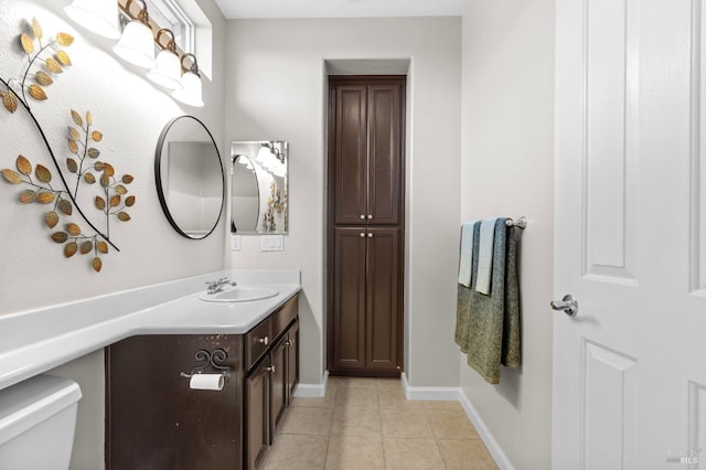 half bathroom featuring tile patterned flooring, baseboards, vanity, and toilet