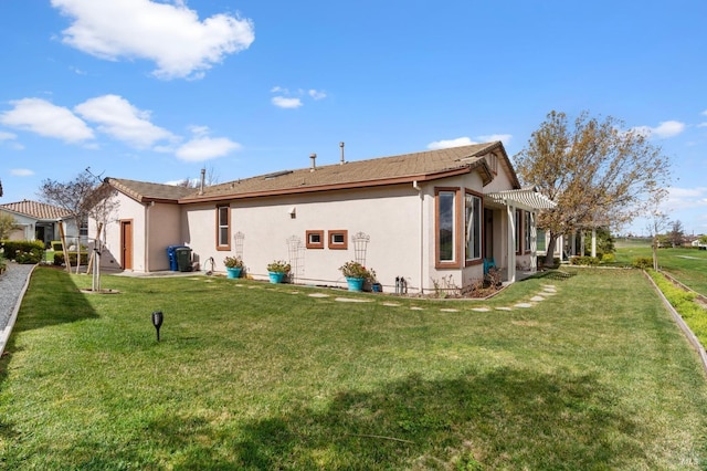 rear view of house featuring a yard, a pergola, and stucco siding