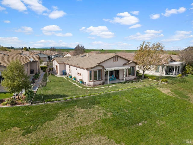 back of house with a patio, a yard, a tiled roof, and stucco siding