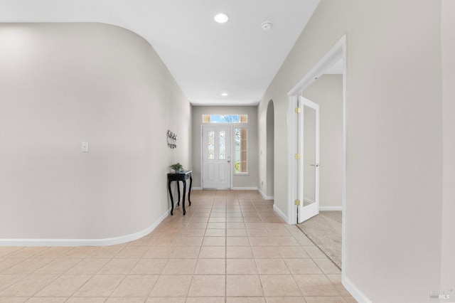 foyer entrance featuring arched walkways, recessed lighting, baseboards, and light tile patterned floors