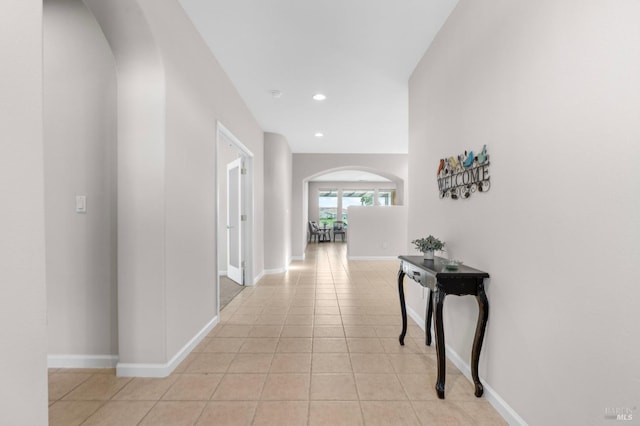 hallway with recessed lighting, baseboards, arched walkways, and light tile patterned flooring