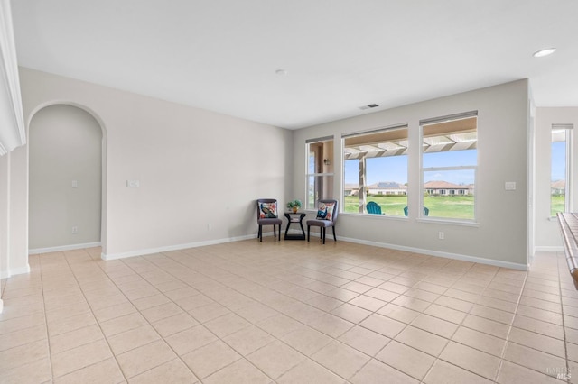 interior space with arched walkways, light tile patterned flooring, visible vents, and baseboards