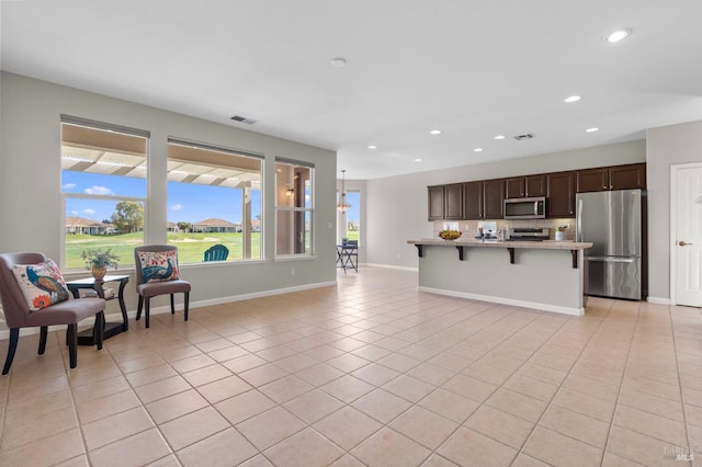 kitchen featuring light tile patterned floors, stainless steel appliances, light countertops, visible vents, and dark brown cabinets
