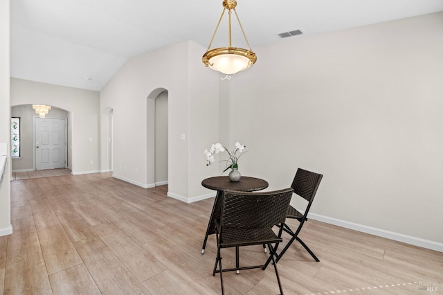 dining area with light wood-style floors, arched walkways, visible vents, and baseboards