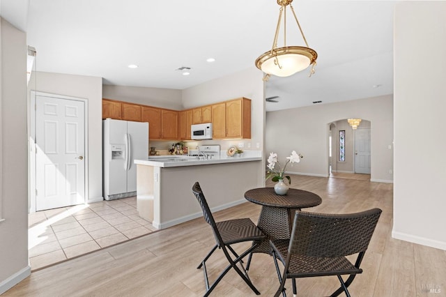 dining room with light wood-type flooring, arched walkways, baseboards, and recessed lighting