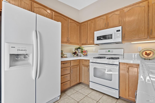 kitchen featuring tile countertops, white appliances, and light tile patterned floors