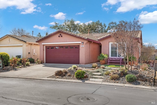 view of front of home with an attached garage, driveway, a tiled roof, and stucco siding