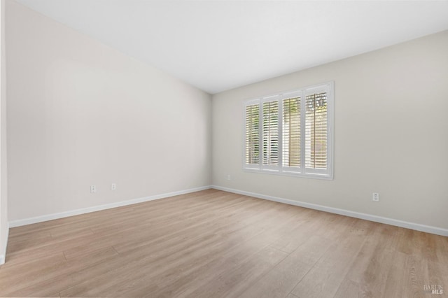 unfurnished room with light wood-type flooring and baseboards