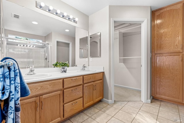 bathroom featuring visible vents, a sink, a shower stall, and tile patterned floors