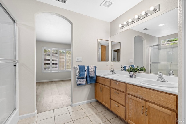 bathroom with a stall shower, visible vents, a sink, and tile patterned floors