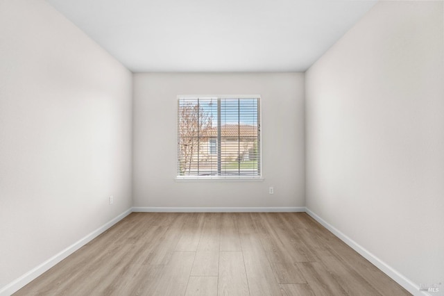 spare room featuring light wood finished floors and baseboards