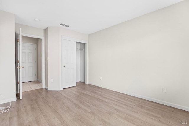 unfurnished bedroom featuring a closet, light wood-type flooring, visible vents, and baseboards