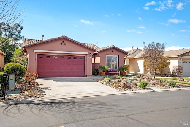 mediterranean / spanish-style home featuring concrete driveway, a tiled roof, an attached garage, and stucco siding