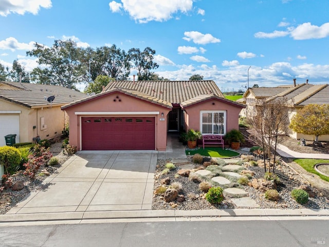 mediterranean / spanish-style house with a garage, a tiled roof, concrete driveway, and stucco siding