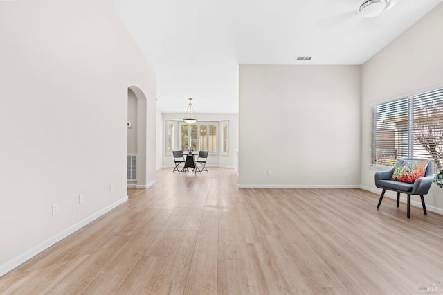 interior space featuring light wood-style flooring, visible vents, and arched walkways