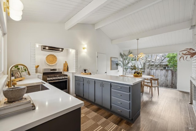 kitchen with vaulted ceiling with beams, gray cabinetry, gas stove, a sink, and a peninsula