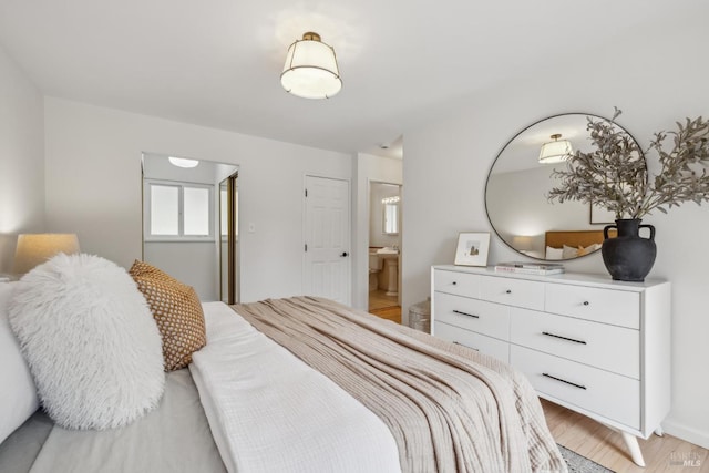 bedroom with ensuite bath and light wood finished floors