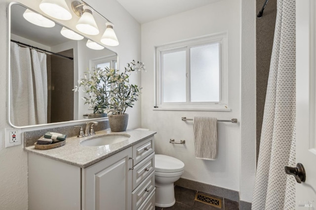 bathroom featuring baseboards, a healthy amount of sunlight, vanity, and toilet