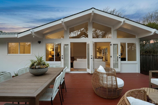 exterior space with outdoor dining area, fence, a wooden deck, and stucco siding