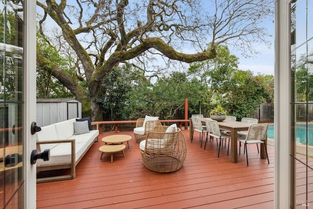 wooden deck with a storage shed, an outdoor hangout area, fence, an outdoor structure, and outdoor dining space