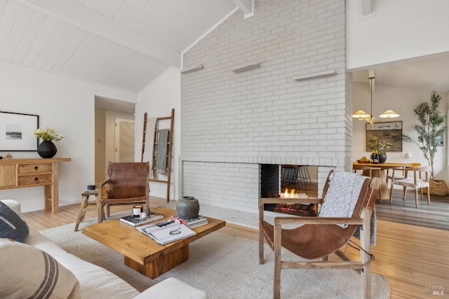 living room featuring high vaulted ceiling, a brick fireplace, beam ceiling, and light wood-style flooring