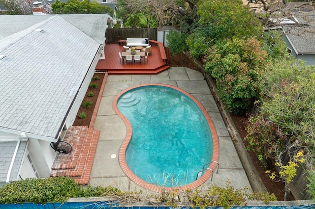 view of swimming pool with a fenced backyard, a storage unit, an outdoor structure, and a wooden deck