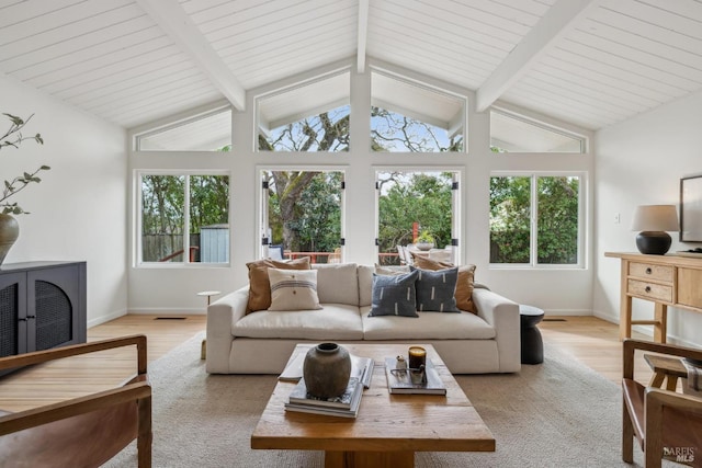 living area featuring lofted ceiling with beams, baseboards, a wealth of natural light, and light wood-style floors