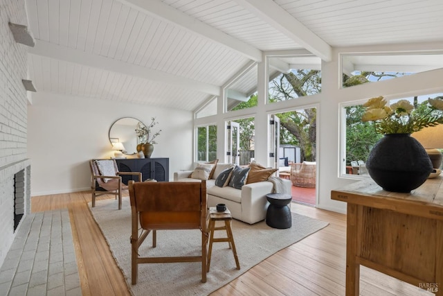 living room featuring light wood-style floors, beam ceiling, a fireplace, and baseboards