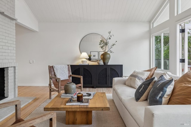 living room with lofted ceiling, wood ceiling, a brick fireplace, wood finished floors, and baseboards