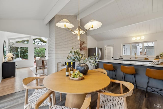 dining room featuring vaulted ceiling with beams and light wood-style flooring