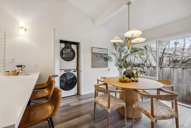 dining room featuring stacked washer and clothes dryer, vaulted ceiling with beams, baseboards, and wood finished floors